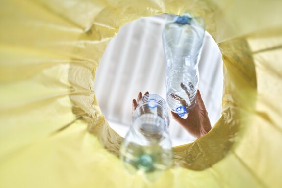 Plastic bottles falling into a yellow garbage bag