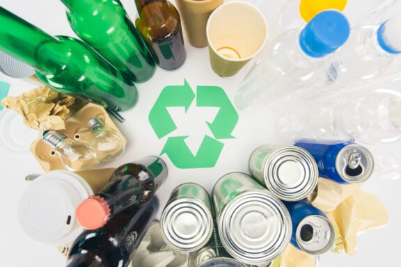 top view of various types of trash with recycle sign on white